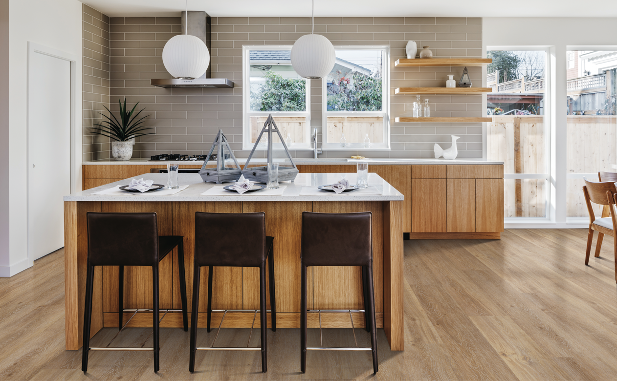 light wood cabinets in kitchen with taupe subway tile backsplash and light wood flooring